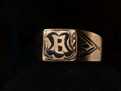 thumbnail of Angled front view of antique c1890 Victorian signet ring in rose gold with black enamel details and the letter "B" on the face. Shown on dark background.
