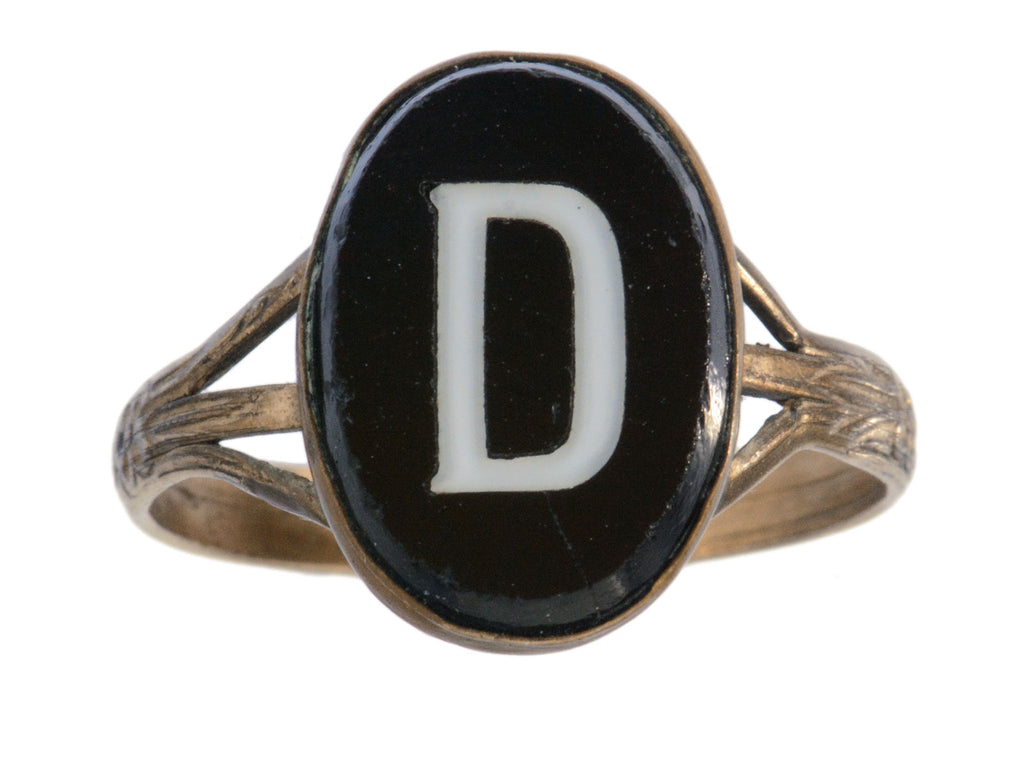 c1890 Victorian signet ring with oval black plaque and white letter "D". Set in brass and shown on white background.