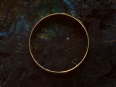thumbnail of Side profile of a petite antique gold signet ring with the letters "I.N" engraved on a rectangular face. Shown on dark background.