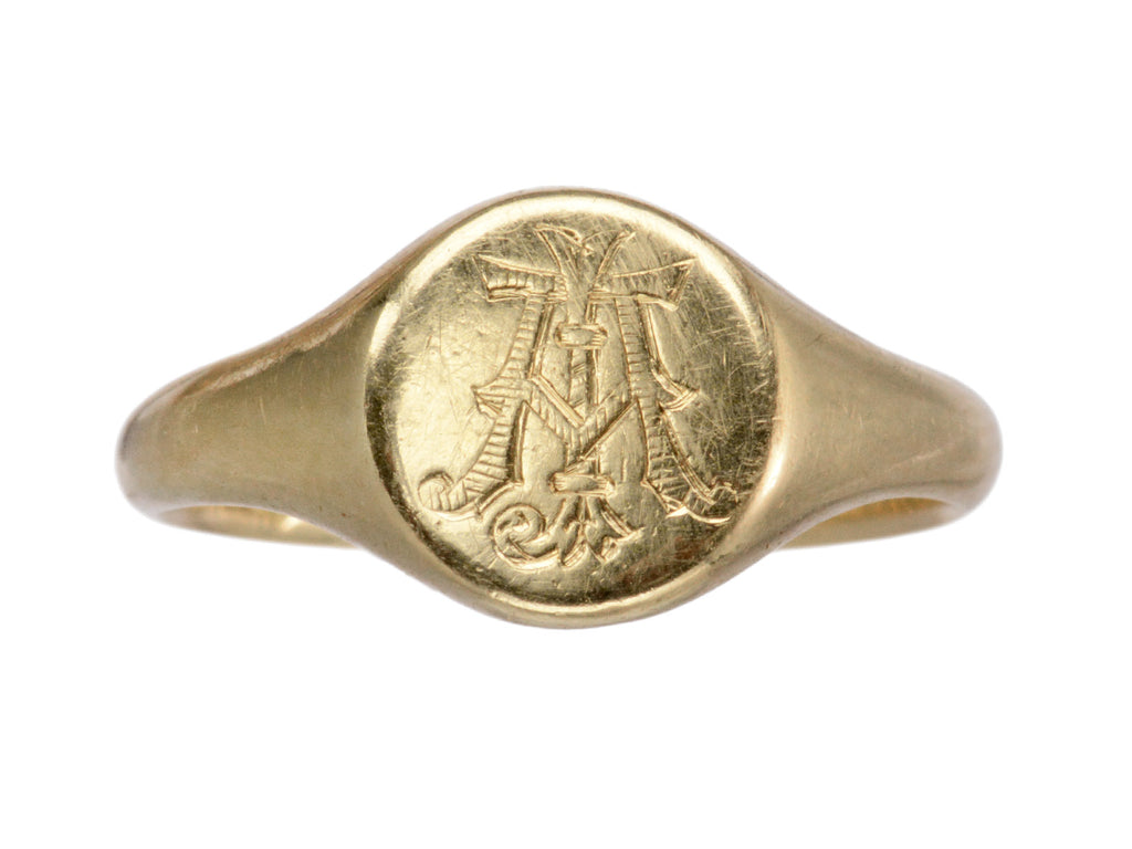An antique 18K gold signet ring with a monogram (letters A and J) engraved on the face. Shown on white background.