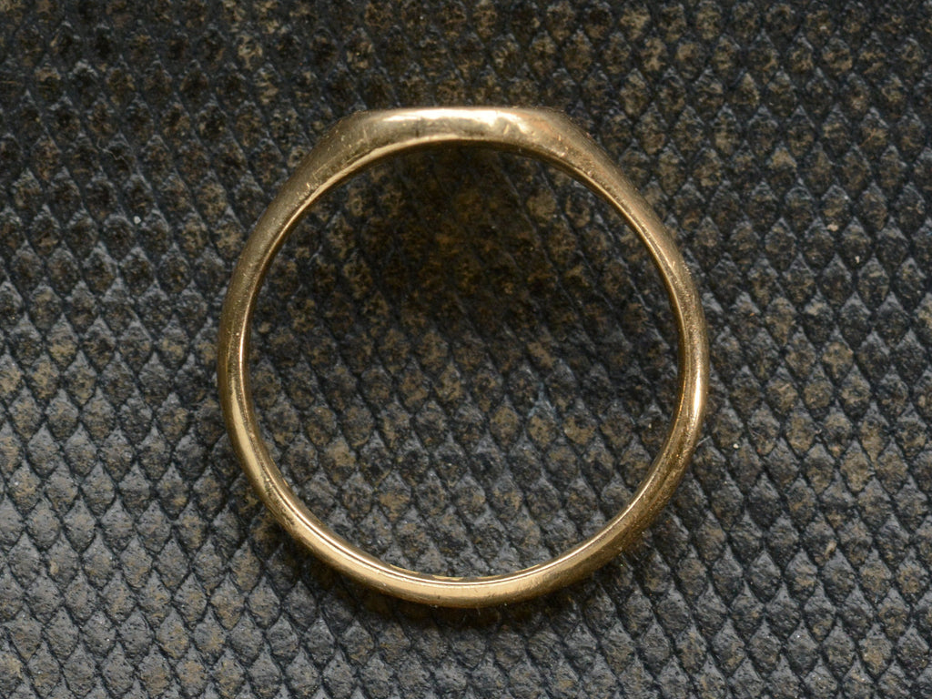 Side profile of an antique 18K gold signet ring. Shown on dark background.