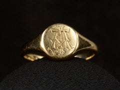 thumbnail of Front view of 18K gold signet ring with a monogram (letters A and J) engraved on the face. Shown on dark background.
