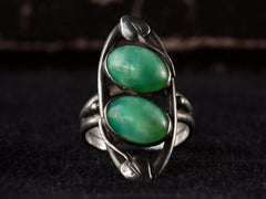 thumbnail of Front view of c1910 Arts & Crafts movement ring with a pair of oval green stones in a silver mounting with vines. On black background.