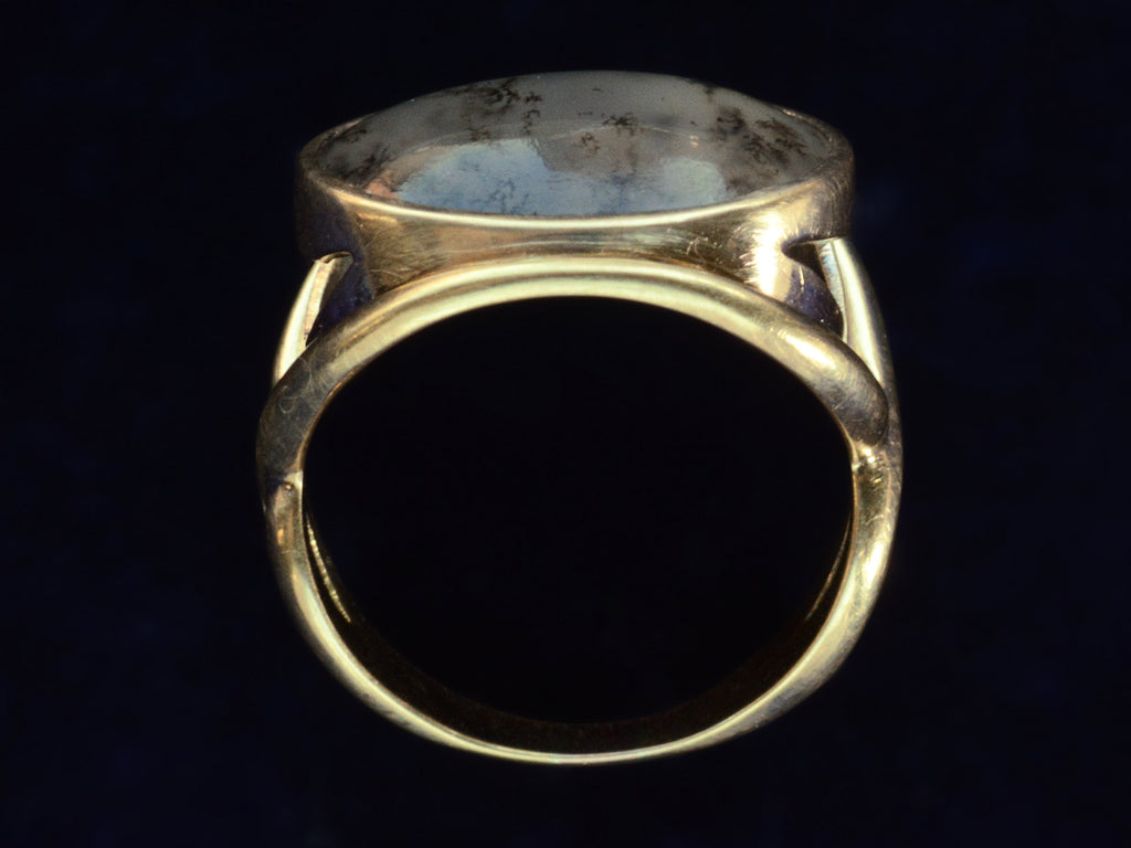 Side profile view of oval dendritic agate ring in yellow gold. Shown on dark background.