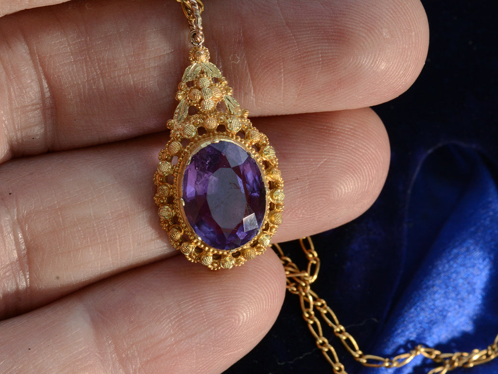 c1880 oval amethyst and yellow gold pendant, shown on hand for scale.