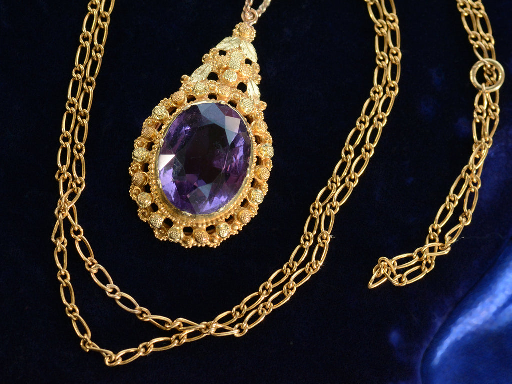 c1880 oval amethyst and yellow gold pendant, shown on dark blue background with detail of chain.