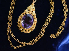 thumbnail of c1880 oval amethyst and yellow gold pendant, shown on dark blue background with detail of chain.