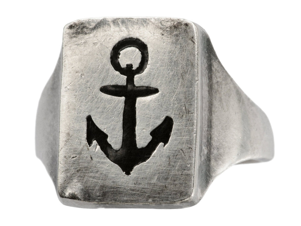 A sterling silver rectangular signet ring with the image of an anchor enameled in black, shown angled on white background.
