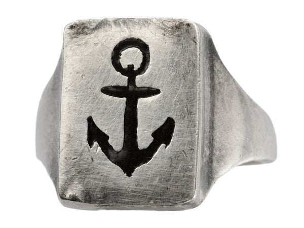 A sterling silver rectangular signet ring with the image of an anchor enameled in black, shown angled on white background.