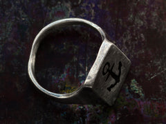 thumbnail of Side profile view of a sterling silver rectangular signet ring with the image of an anchor enameled in black, shown on dark background.