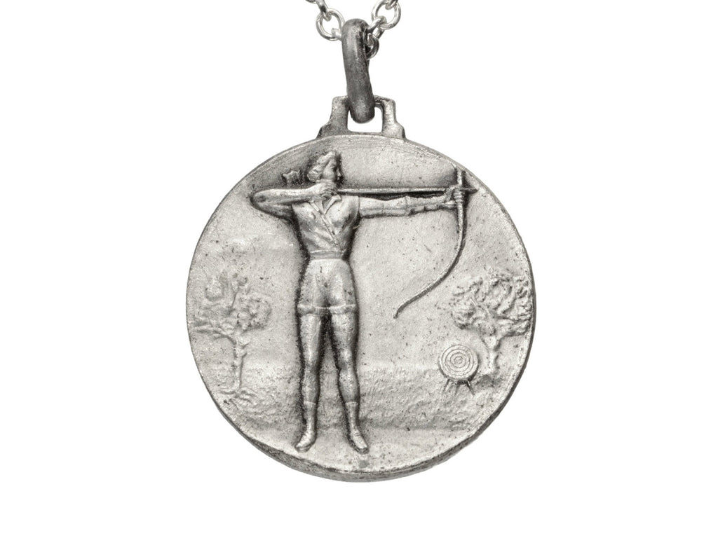 Detail of a vintage white metal archery medal with an archer pictured in relief. Shown on white background.