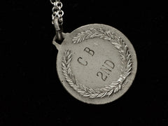 thumbnail of Reverse side detail of a vintage white metal archery medal inscribed "C B 2ND" on the back with an "ITALY" mark also showing. Shown on black background.