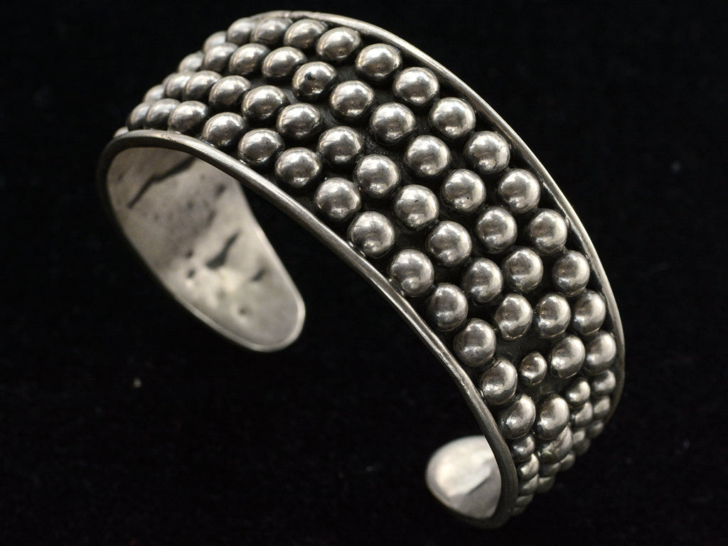 A vintage wide silver cuff bracelet featuring a textured, beaded outer band and a smooth polished inner band, shown against a solid black background.
