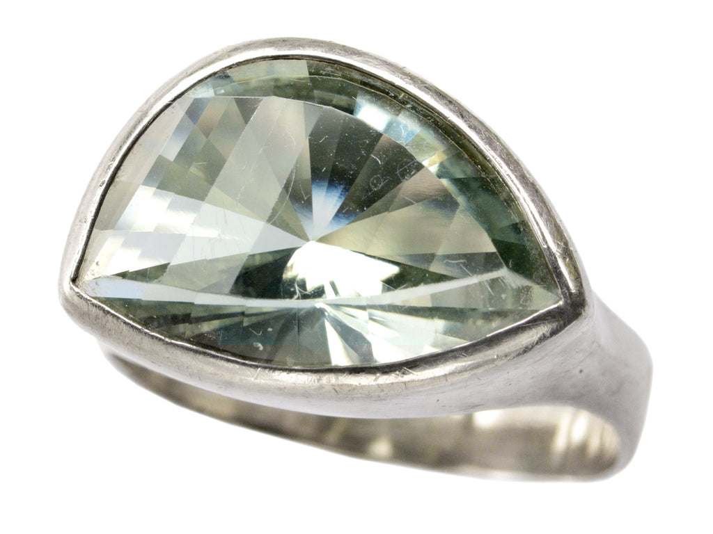 Angled view of silver ring with faceted light green eye-shaped stone, shown on white background.