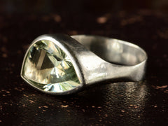 thumbnail of Side view of silver ring with faceted light green eye-shaped stone, shown on dark background.
