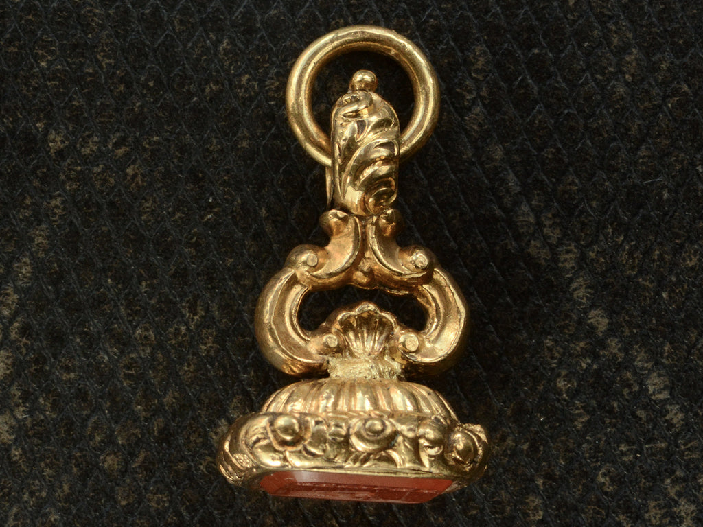 Side profile view of Georgian-era gold fob with a carnelian intaglio shown on dark textured background.