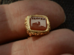 thumbnail of Detail view of Georgian-era gold fob with a carnelian intaglio carved with the word "BEWARE" in mirror image and the image of a mousetrap and mouse, shown held between fingers.