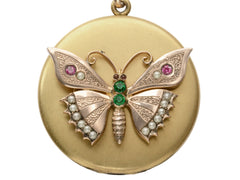 thumbnail of A round Victorian gilt locket with a rose gold butterfly mounted on the front, detailed with pearls and red and green paste. Shown on white background.