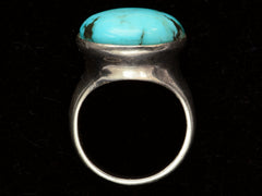 thumbnail of Side profile view of large oval turquoise and silver ring on black background.