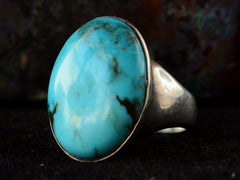 thumbnail of Angled view of large oval turquoise and silver ring on dark background.