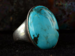thumbnail of Left angled view of large oval turquoise and silver ring on dark background.