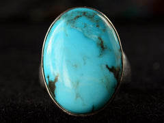 thumbnail of Front view of large oval turquoise and silver ring on dark background.