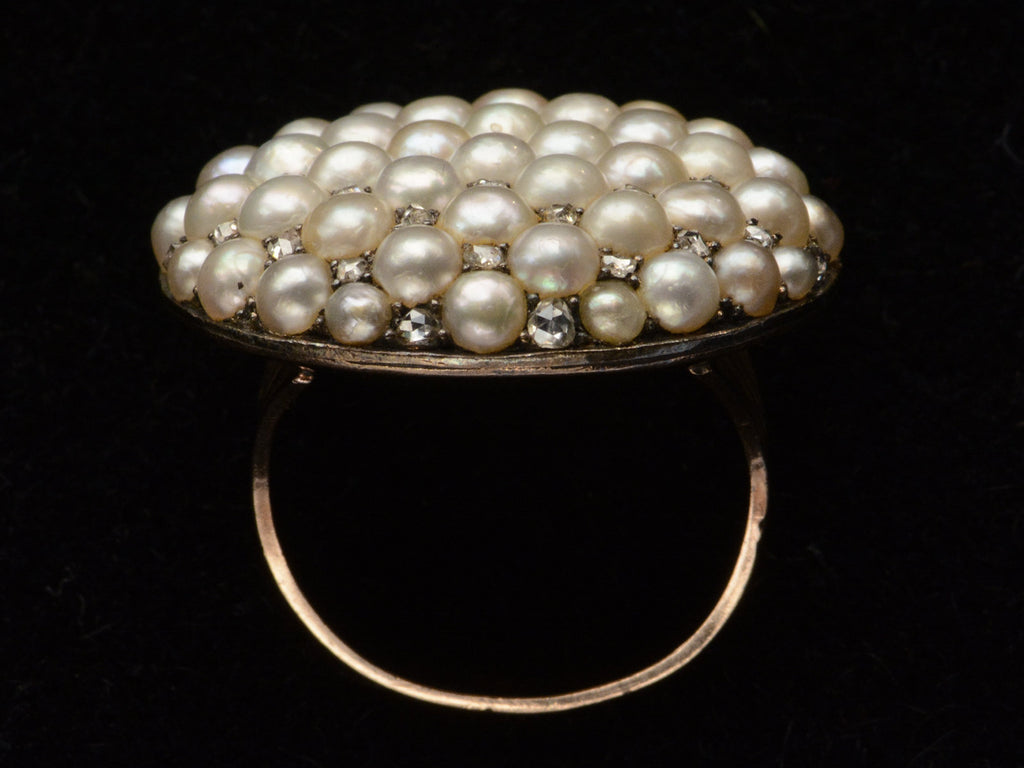 Side profile view of Victorian ring with a large luster pearls and rose cut diamonds, set in rosy-yellow gold, shown on dark background.