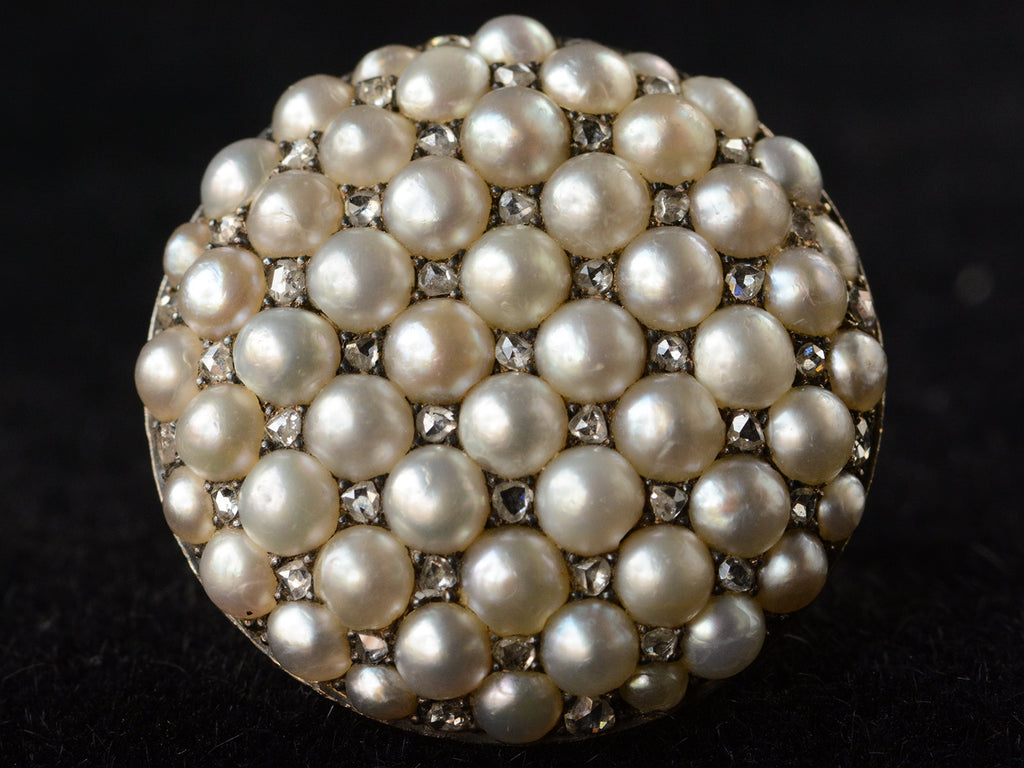 Front profile view of Victorian ring with a large luster pearls and rose cut diamonds, set in rosy-yellow gold, shown on dark background.