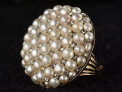 thumbnail of Right angled view of Victorian ring with a large luster pearls and rose cut diamonds, set in rosy-yellow gold, shown on dark background.
