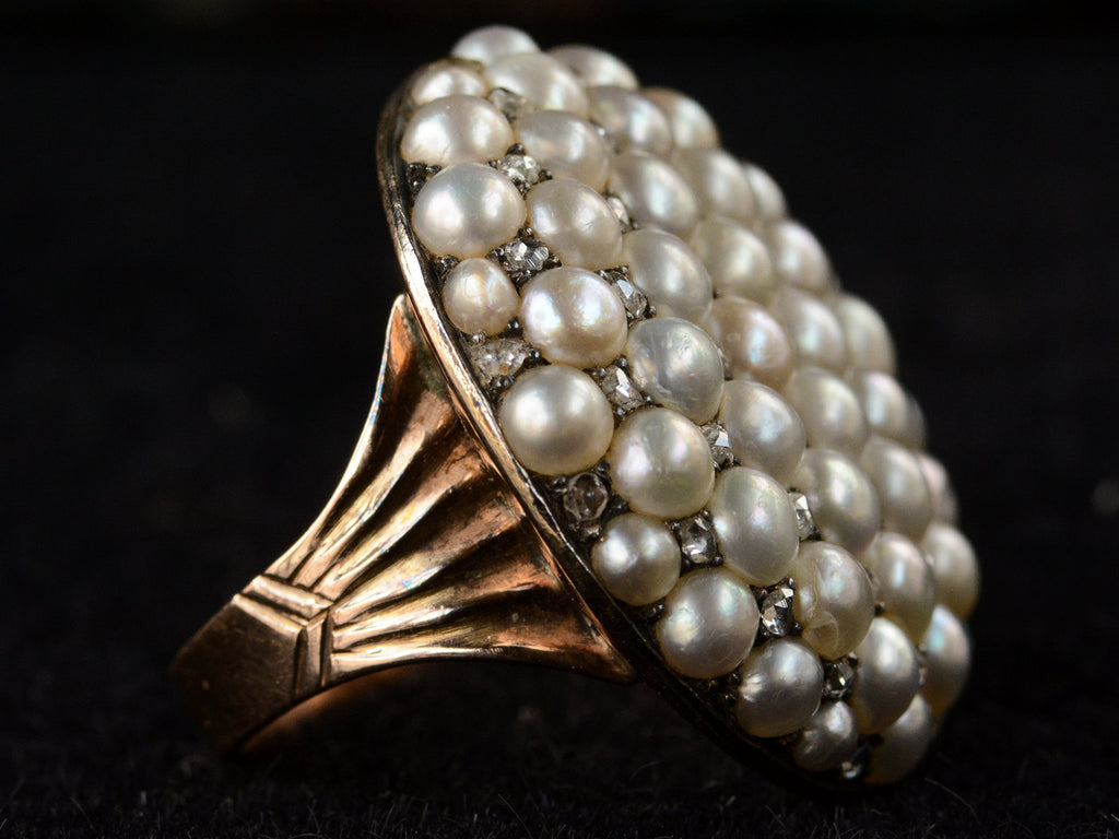 Left side view of Victorian ring with a large luster pearls and rose cut diamonds, set in rosy-yellow gold, shown on dark background.