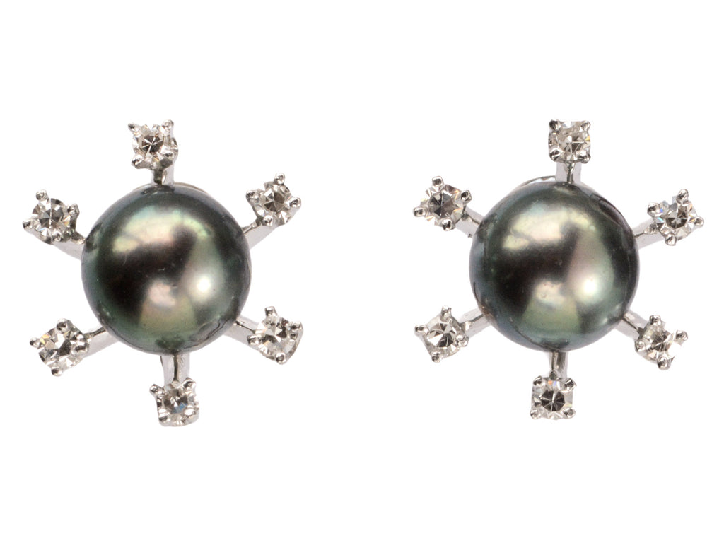 A pair of vintage starburst stud earrings featuring a dark green-gray cultured pearls in a white gold prong setting, surrounded by six small clear diamonds on a white background.