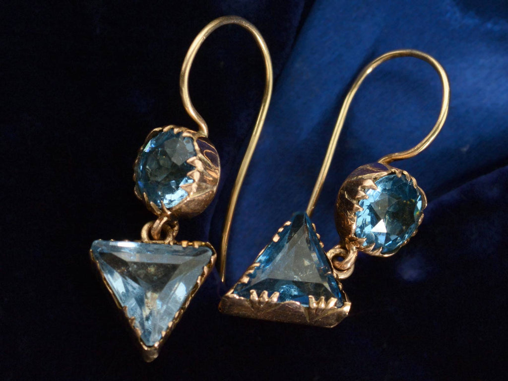 Detail view of c1840 Blue Paste Crystal Earrings in Gold (shown on dark blue background)