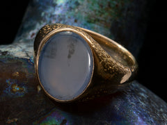 thumbnail of Detail view of antique gold signet ring with oval blue chalcedony face, on dark background.
