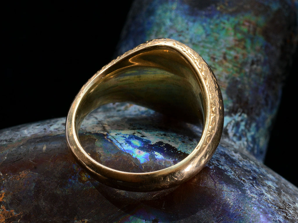 Reverse side view of antique gold signet ring with oval blue chalcedony face, on dark background.