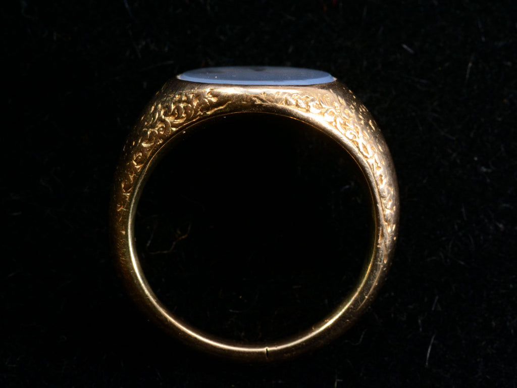 Side profile view of antique gold signet ring with oval blue chalcedony face, on dark background.