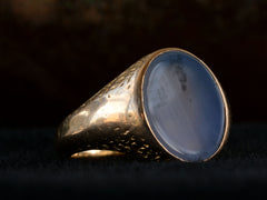 thumbnail of Left angled view of antique gold signet ring with oval blue chalcedony face, on dark background.