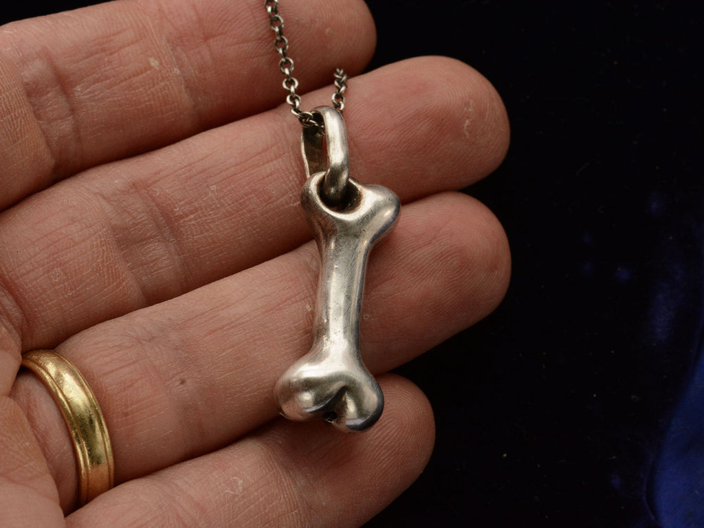 Vintage silver bone-shaped pendant on hand