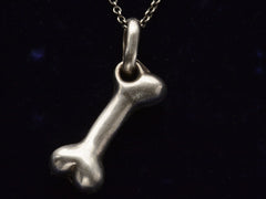 thumbnail of Vintage silver bone-shaped pendant on a dark background