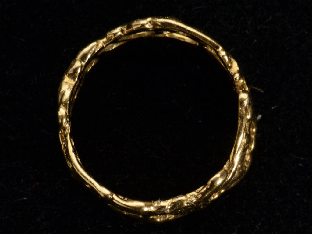 Side profile view of wide brutalist wedding band in 18k yellow gold, shown on black background.