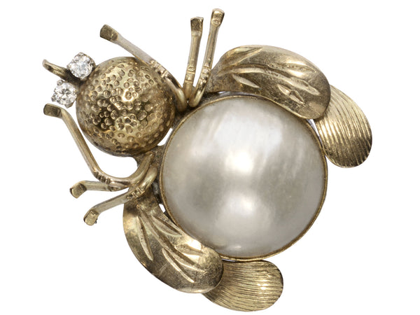A yellow gold insect brooch with diamond eyes and a pearl abdomen, shown on white background.