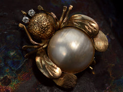thumbnail of A yellow gold insect brooch with diamond eyes and a pearl abdomen, shown on dark background.