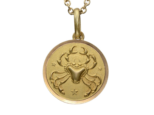 Detail of round gold pendant with a crab, shown on white background.