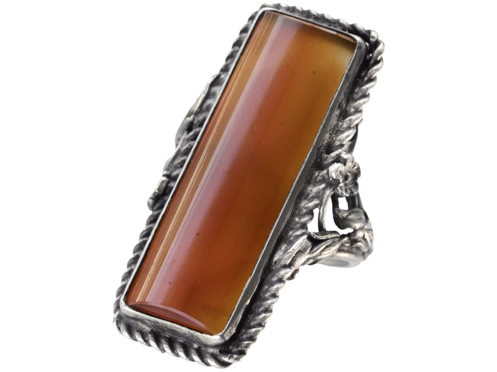 A vintage silver ring with intricate detailing and a long rectangular carnelian stone, shown on white background.