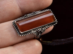 thumbnail of A vintage silver ring with intricate detailing and a long rectangular carnelian stone, shown on finger.