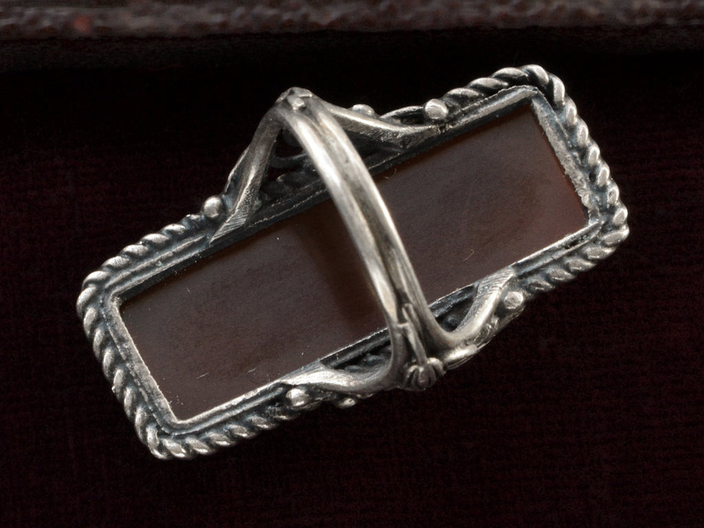Inside view of vintage silver ring with intricate detailing and a long rectangular carnelian stone, shown on dark background.