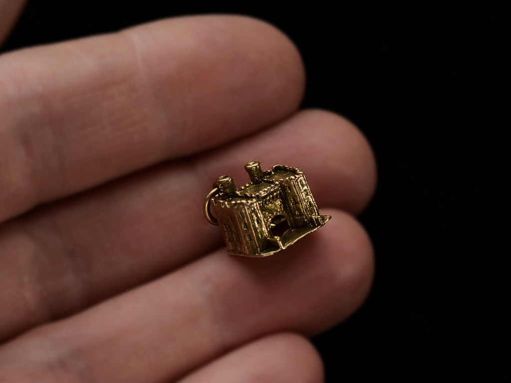 A castle charm in gold, on hand.