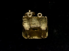 thumbnail of Top view of castle charm in gold, on black background.