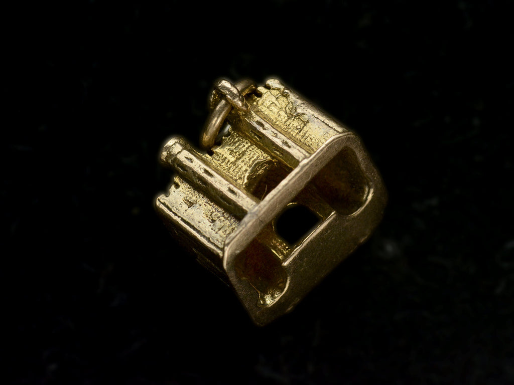 Bottom view of castle charm in gold, on black background.