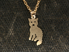 thumbnail of A 2-dimensional yellow gold cat charm hanging on chain, shown dark textured background.