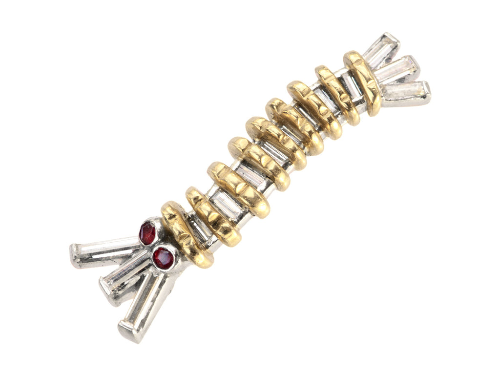 A vintage white and yellow gold caterpillar brooch with ruby eyes and diamond baguettes, on white background.
